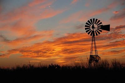 Windmill silhouette against a vibrant sunset sky.