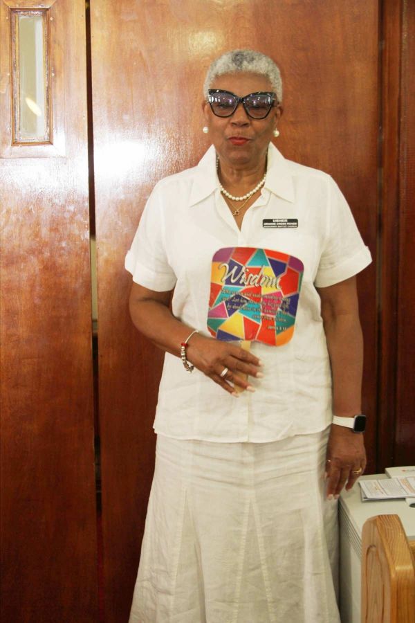 Woman in white holding a colorful fan with text.