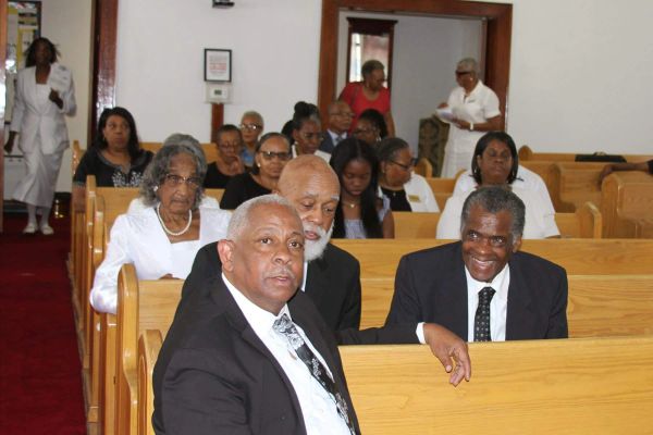 People sitting in wooden pews inside a church.