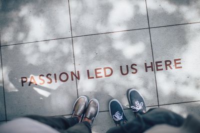 overhead view of two people looking down at the sidewalk with words "passion led us here" written on