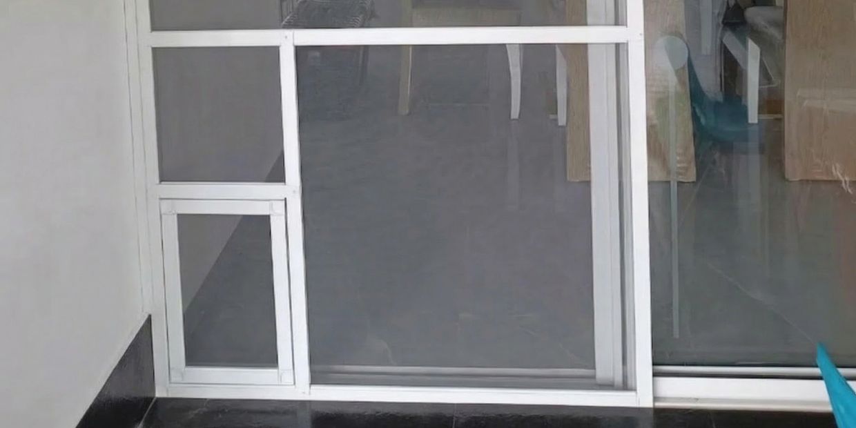 White-framed glass sliding door with a smaller pet door insert at the bottom left.