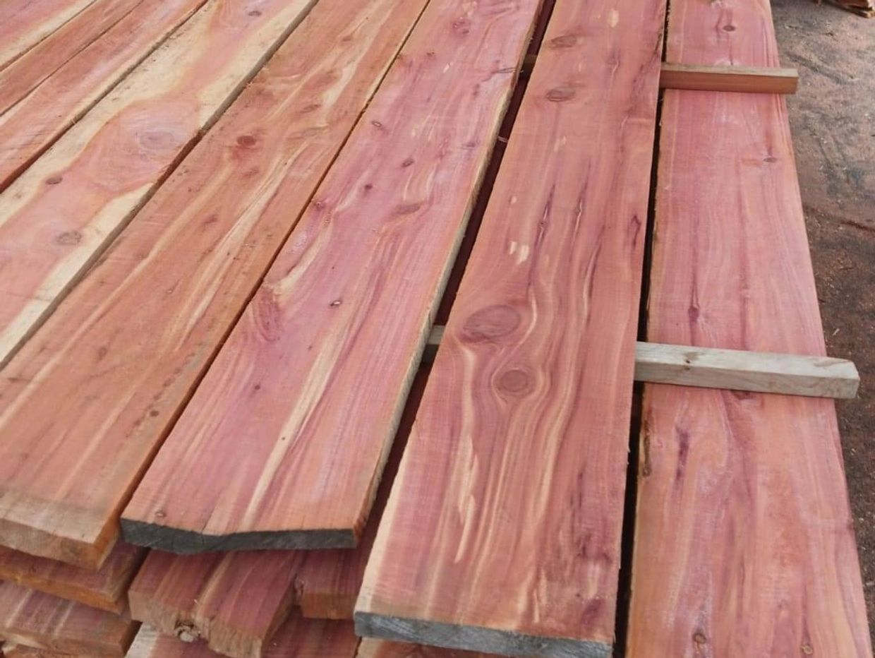 Stack of reddish wooden planks with natural grain patterns.