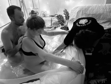 Couple in water with a support person during a birthing process.