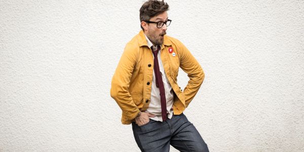 Surprised man in yellow jacket and glasses.
