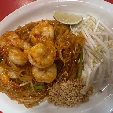 Shrimp pad thai with peanuts, bean sprouts, and lime wedge on a white plate.