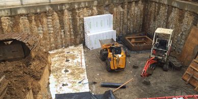 Preparing a large basement excavation for the structural slab, showing the formation of the sump cha