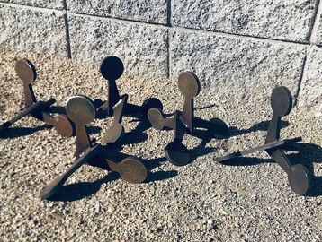 Metal targets casting shadows on gravel.