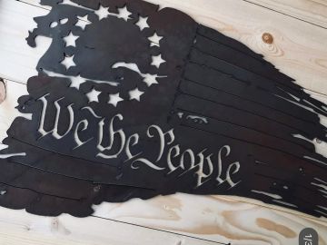 Metal artwork of the U.S. flag with 'We the People' text.