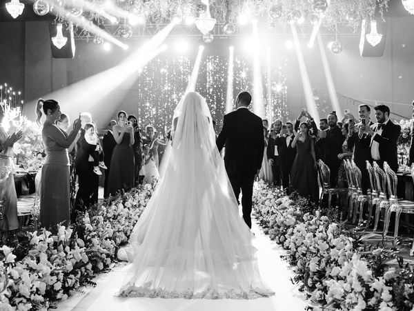 A luxury wedding moment as the bride and groom walk down the aisle, a pathway of exquisite florals.