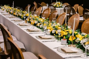 Elegant table setup with yellow flowers and candles for a formal event.