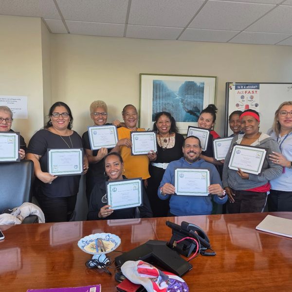 Group of people proudly holding certificates in a meeting room.