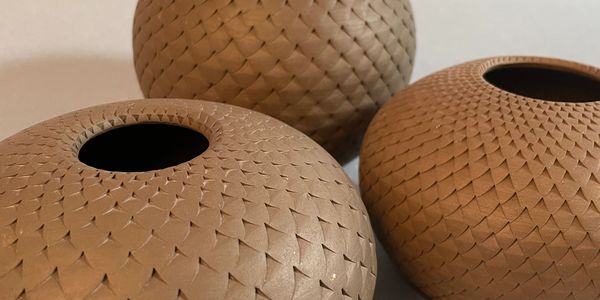 Three brown textured spherical vases with small openings on top.