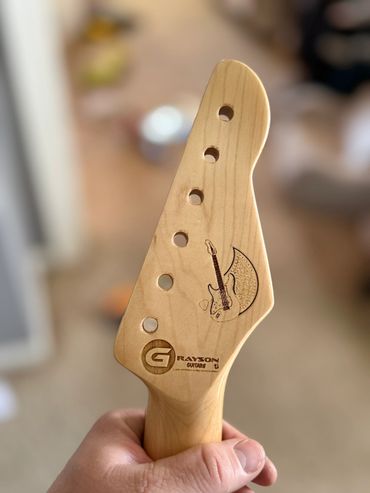 Close-up of a wooden guitar headstock with Grayson Guitar logo.