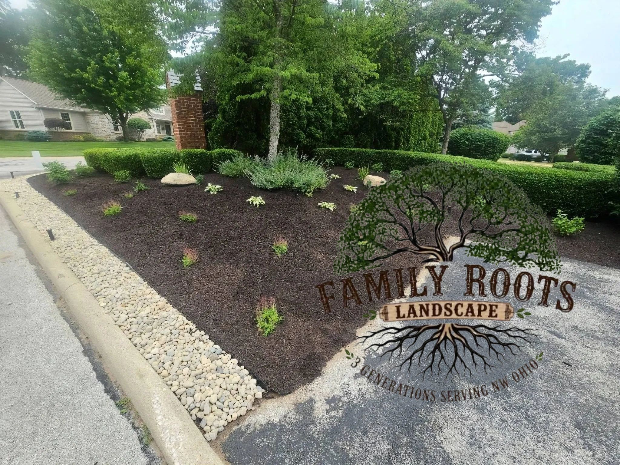 Freshly mulched garden bed with new plants and decorative rocks.