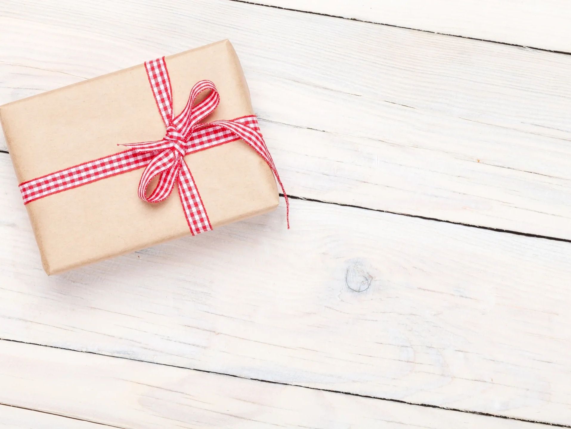 A Gift box with a red ribbon on the wooden table