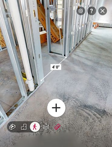 Metal framing and plumbing pipes inside a construction site with a 4-foot measurement.