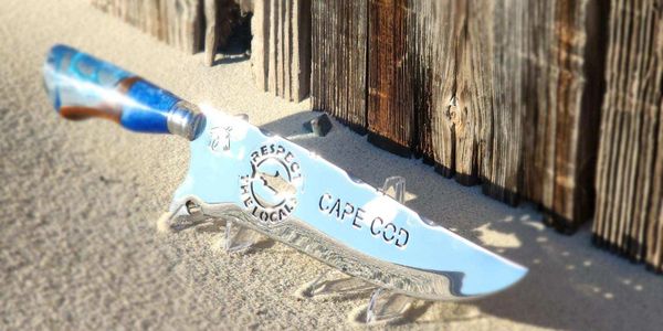 A shiny knife with "Cape Cod" and "Respect the Block" engraved on the blade.