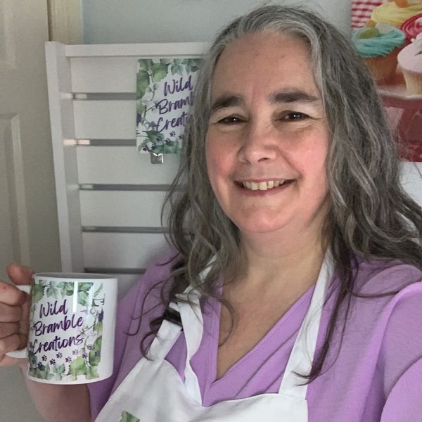 Owner of Wild Bramble Creations, holding a printed logo mug.