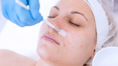 Woman receiving a facial treatment with a brush.