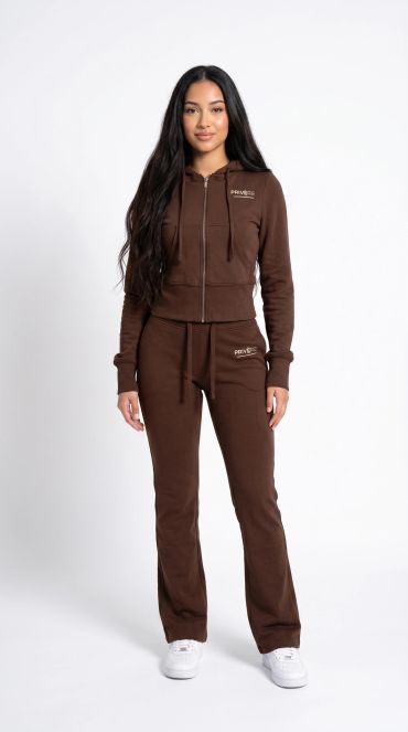 Woman wearing a brown tracksuit with white sneakers.