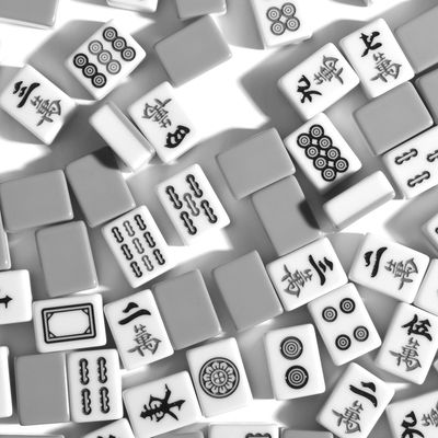Scattered Mahjong tiles with Chinese characters and symbols on a white surface.
