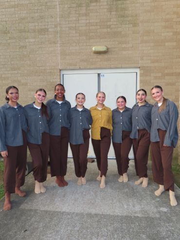 Group of women in coordinated outfits standing outside a building.