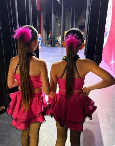 Two dancers in pink costumes backstage.