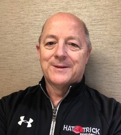 A middle-aged man in a black zip-up jacket smiling.