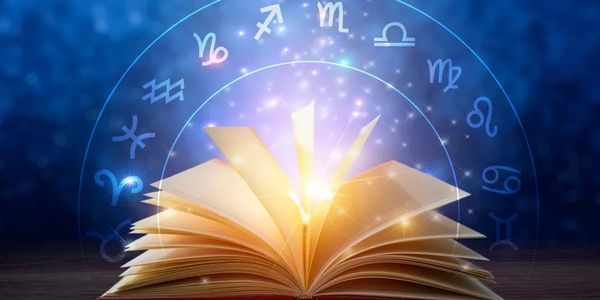 Open book with glowing zodiac symbols above it.