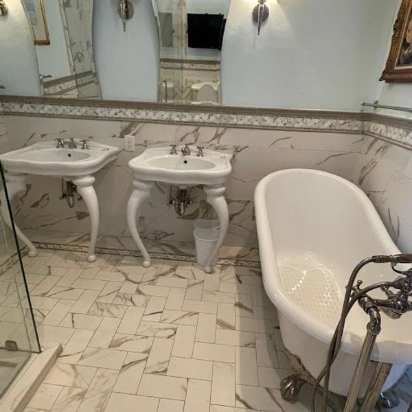 Elegant bathroom with clawfoot tub and twin pedestal sinks.