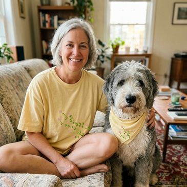 Smiling woman in yellow shirt sitting with her fluffy dog wearing a matching bandana.