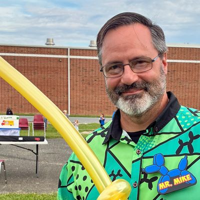 Man smiling with balloon and colorful shirt.