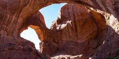 Natural rock arches with sunlight illuminating red sandstone.