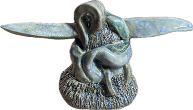Blue ceramic sculpture of a snake coiled on a textured base with extended wings.