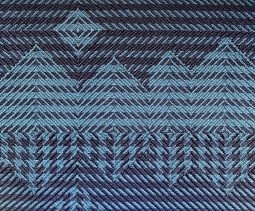 Blue and black geometric patterned textile with zigzag and triangular shapes.