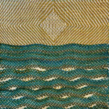 Close-up of woven fabric with geometric patterns in gold and teal.