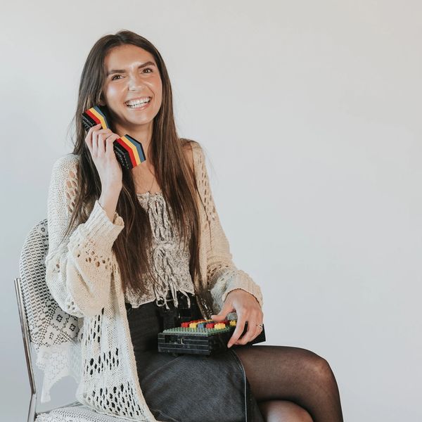 Smiling woman playing with colorful wooden blocks shaped like a phone.