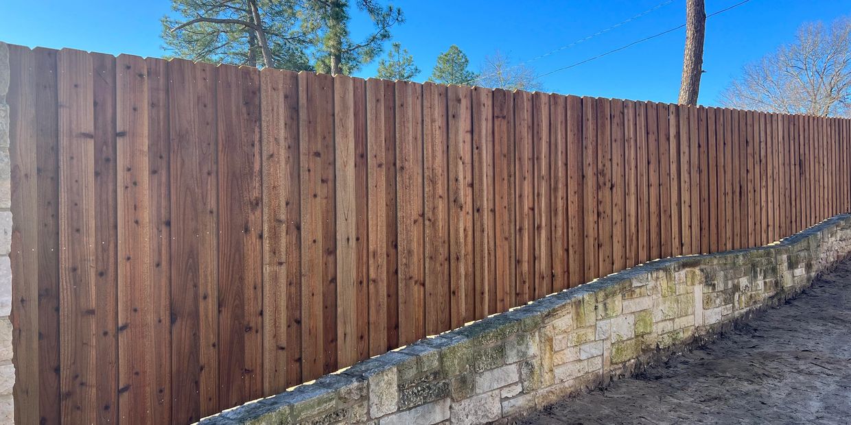 WOODEN FENCE ON TOP OF DECORATIVE ROCK BASE