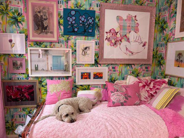 A very pink room: pink palm and flamingo wall paper, various art nieces on the wall, a fuzzy pink be
