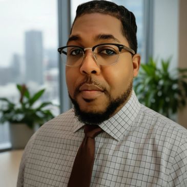 Man wearing glasses and a tie in an office.