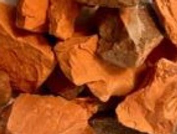 A pile of reddish-brown rocks or clay chunks on a light surface.