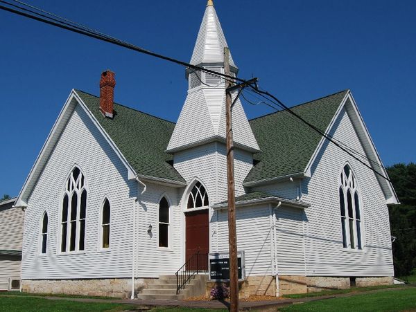 White church building with green roof and steeple.