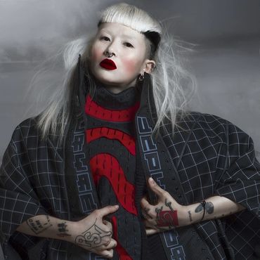 Fashion model with bold makeup and unique hairstyle.