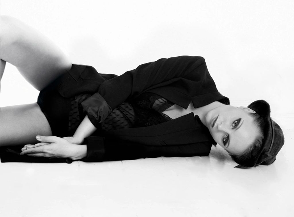 Black and white photo of a woman lying down in stylish attire.