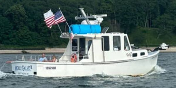 White fishing boat named Molly G with American flags on the water.