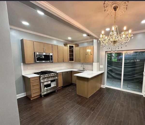 Modern kitchen with wooden cabinets and chandelier.