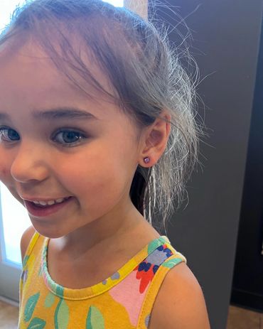 Little girl showing off her lobe piercings.