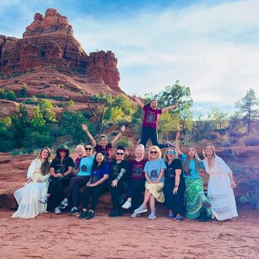 Group of people posing joyfully in a desert landscape with red rock formations.