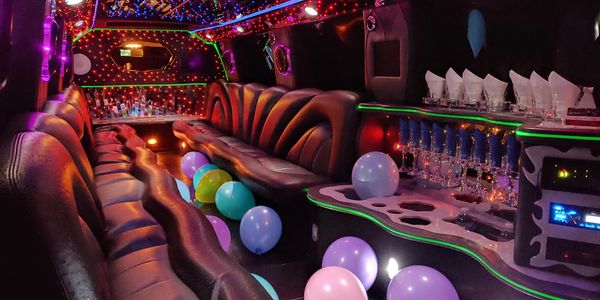 Luxurious limousine interior with colorful balloons and vibrant lighting.