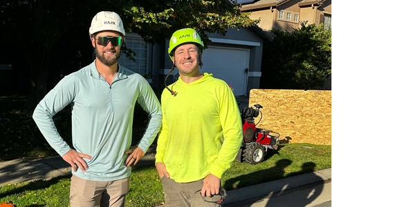 Two tree climbers in hard hats at a residential home getting ready to do a tree removal and clean up